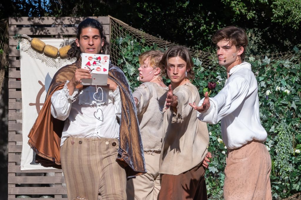 Four boys acting on stage in a Shakespeare play.